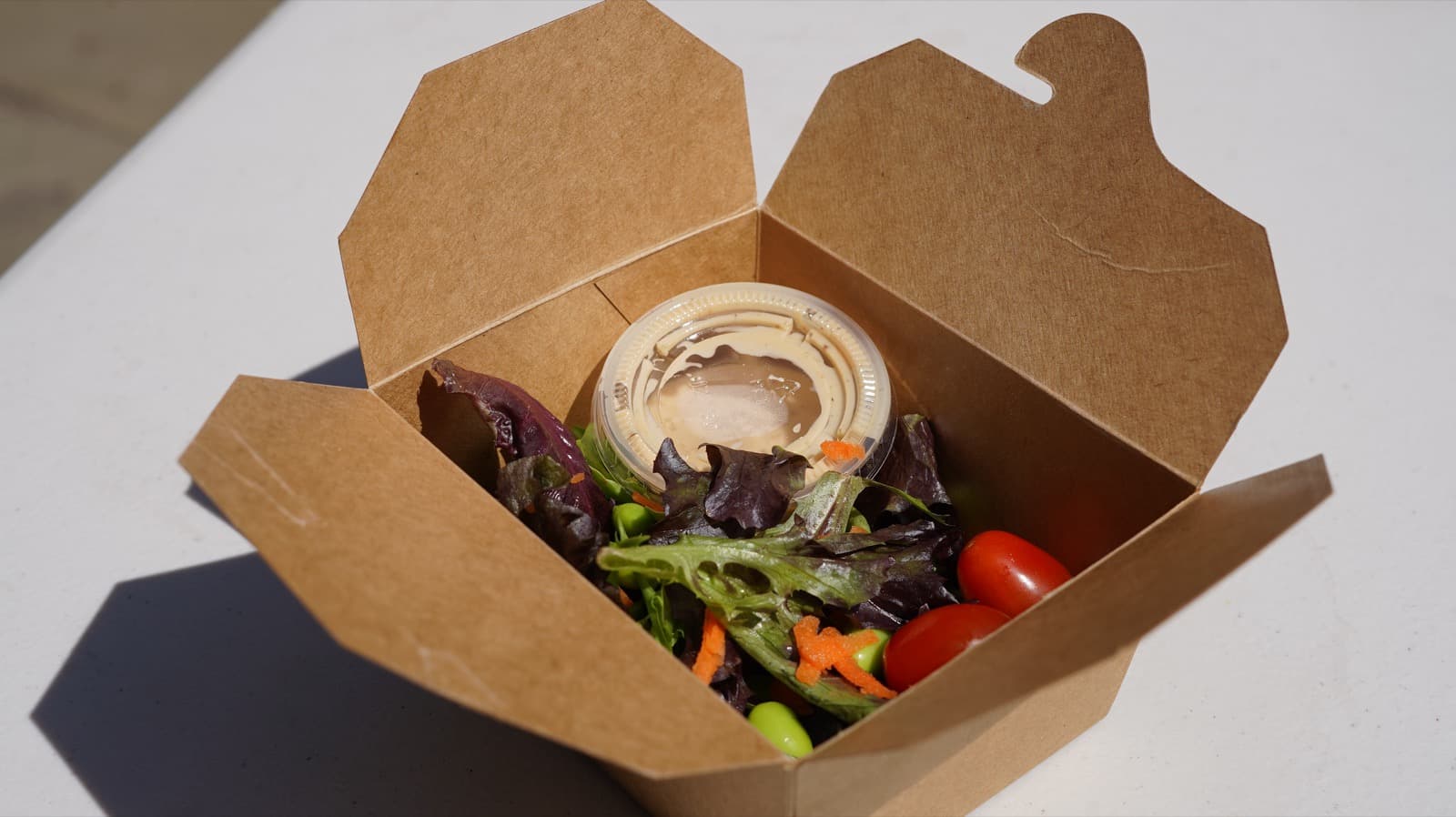 Mixed green salad starter in a kraft bento box